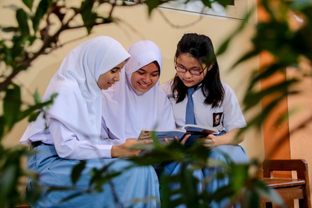 A group of Indonesian students studying a book together.